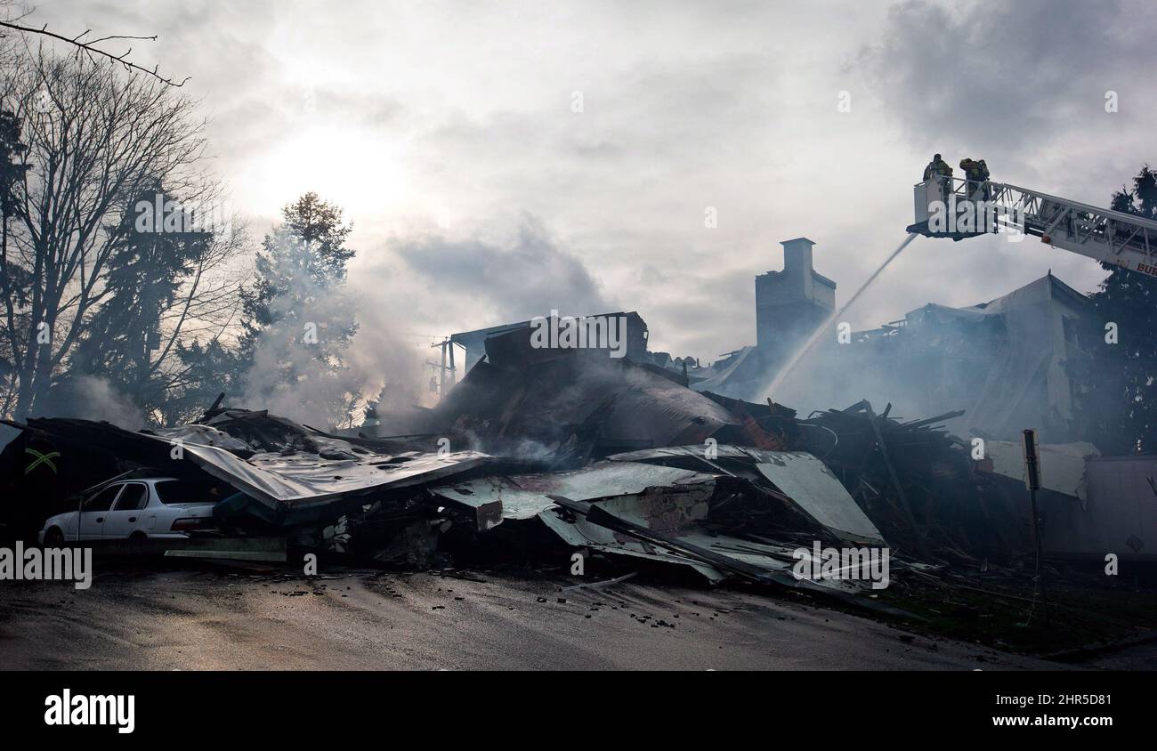Les pompiers dirigent l'eau sur les points chauds alors que la fumée s'élève des restes d'un immeuble d'appartements après un incendie à trois alarmes à Burnaby, en Colombie-Britannique, le dimanche 17 février 2013. Les pompiers ont pris la course pour secourir les résidents qui criaient tout en abattant le feu du matin qui a englouti le bâtiment, détruisant 138 maisons. LA PRESSE CANADIENNE/Darryl Dyck Banque D'Images