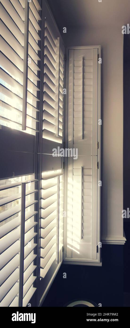 Image verticale de la lumière qui brille à travers la fenêtre avec des volets de plantation Banque D'Images