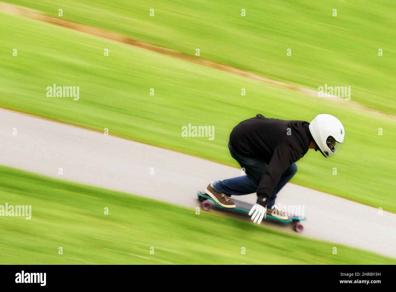 Il vit la vie dans la voie rapide. Photo d'un homme qui fait du skateboard sur une voie à grande vitesse sur son plateau. Banque D'Images