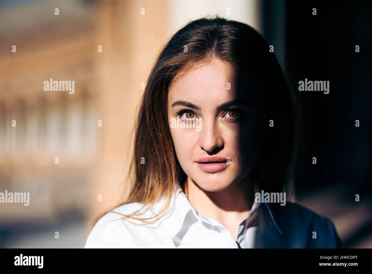 Gros plan de la jeune femme caucasienne avec un regard intense entre le soleil et l'ombre Banque D'Images