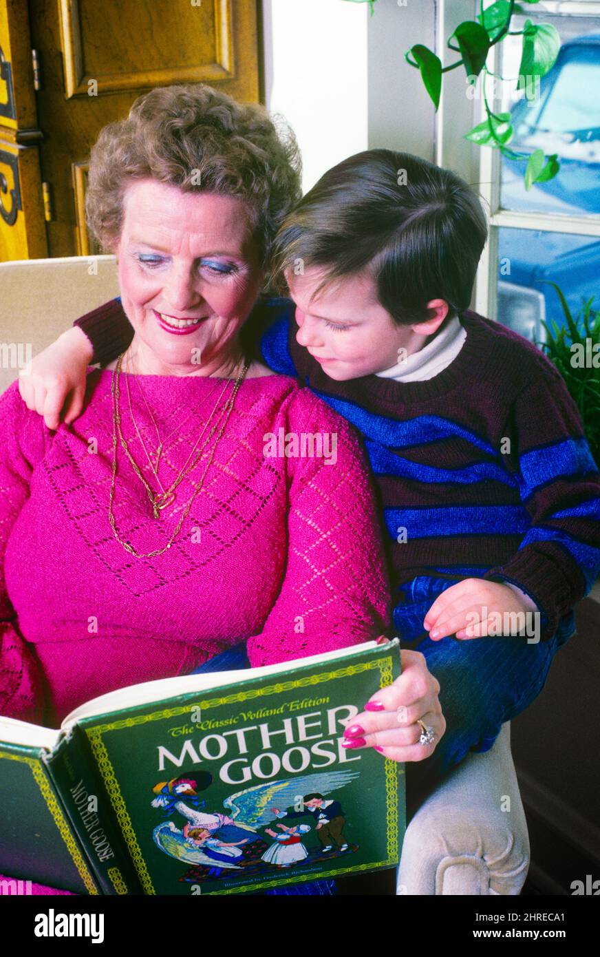 1980S PETIT-FILS ASSIS SUR LE BRAS DE LA CHAISE, BRAS AUTOUR DE LA FEMME, SA GRAND-MÈRE, COMME ELLE LE LIT DE SA MÈRE GOOSE LIVRE - KJ11212 TRA001 HARS GRAND-MÈRE TEMPS VIEUX NOSTALGIE VIEILLE MODE 1 STYLE JUVÉNILE COMMUNICATION TRAVAIL D'ÉQUIPE GRANDS-PARENTS FORTS HEUREUX FAMILLES JOIE STYLE DE VIE SATISFACTION AÎNÉS FEMMES GRAND-PARENT MAISON VIE COPIE ESPACE AMITIÉ DEMI-LONGUEUR FEMMES PERSONNES S'OCCUPANT HOMMES SENIOR ADULTE SENIOR SENIOR FEMME GOOSE BONHEUR VIEILLESSE OLDSTERS GAIETÉ OLDSTER SA ELLE COMME DE SUR LES GRANDS-MÈRES SOURIT CHANDAILS ANCIENS CONNEXION PETIT-FILS JOYEUSE MÈRE GOOSE ATTACHEMENT PERSONNEL AFFECTION ÉMOTION Banque D'Images