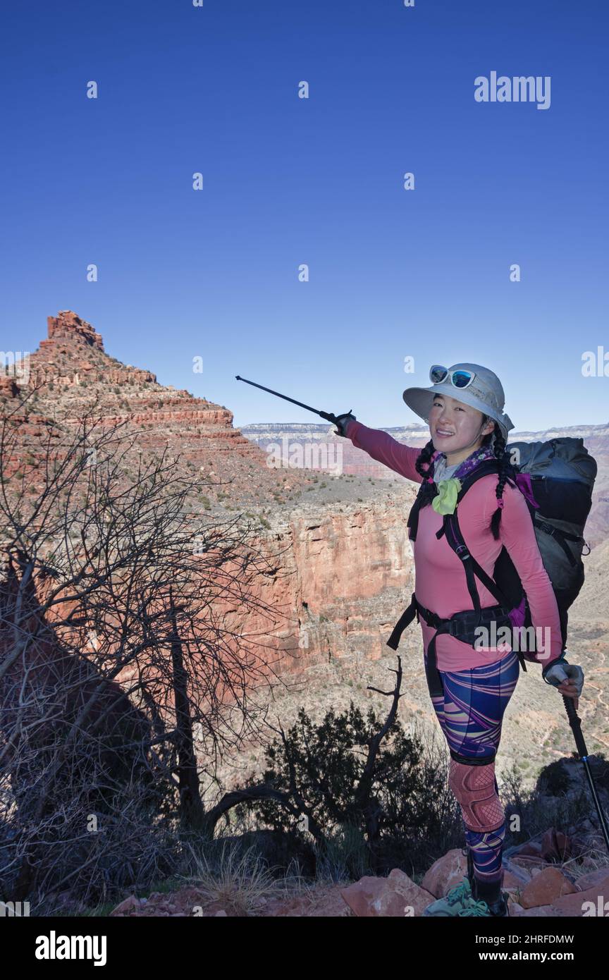 Une femme asiatique de randonnée dans le Grand Canyon sur le Bright Angel Trail pointe au Battleship avec son poteau de trekking Banque D'Images