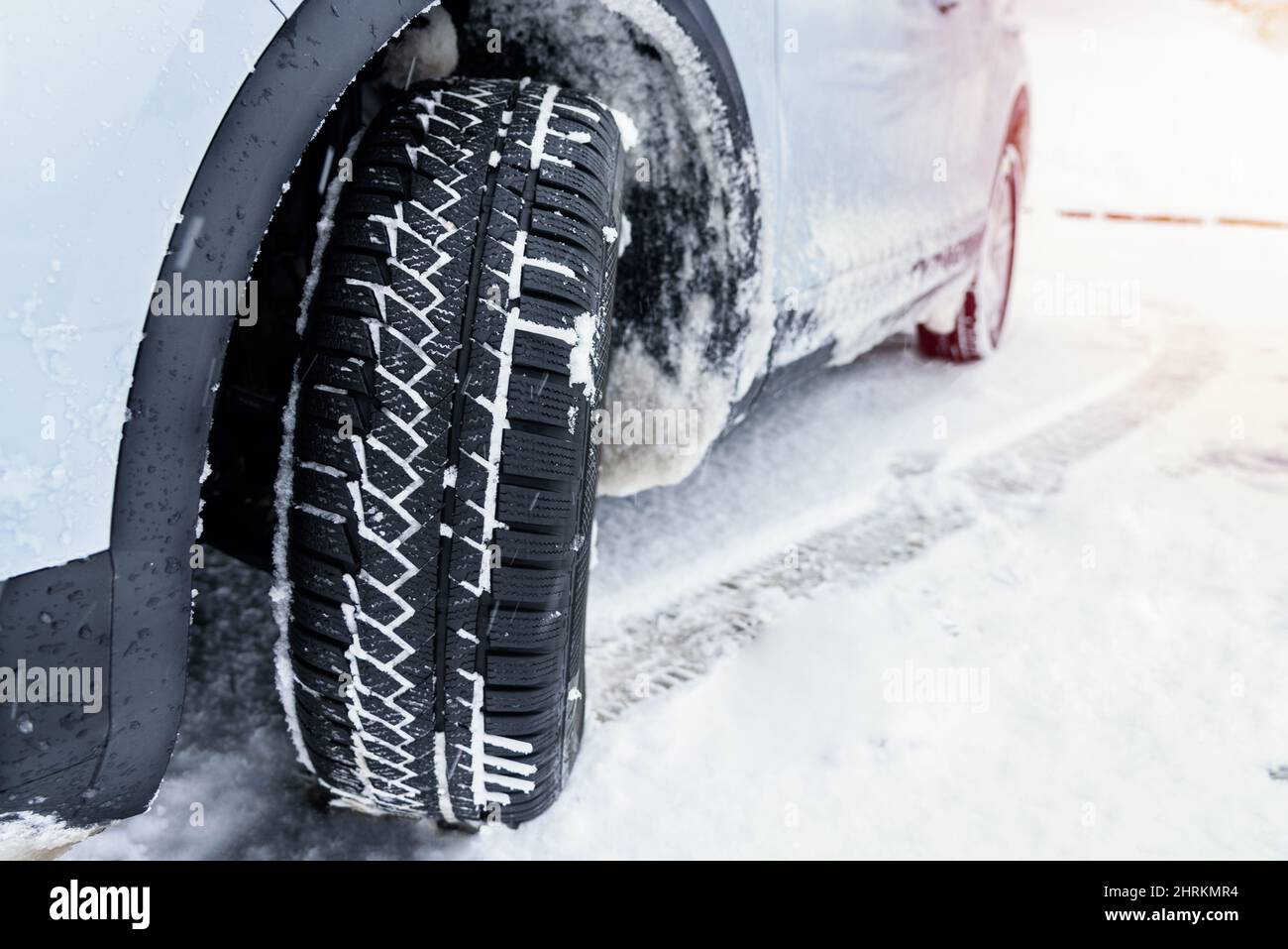 Voiture équipée de pneus neige sur une route alpine enneigée glissante pendant un blizzard Banque D'Images