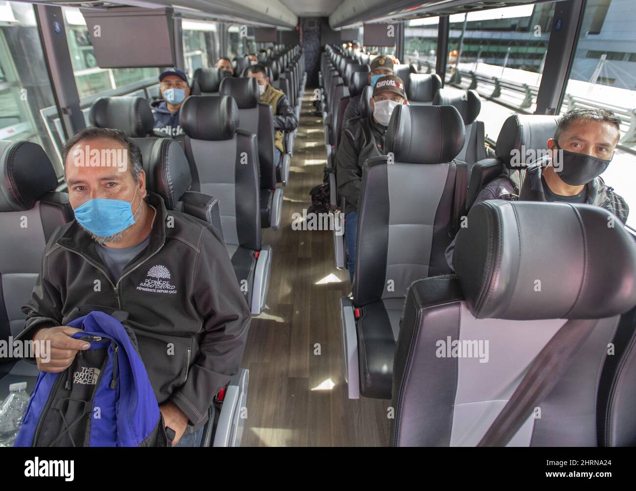 Les travailleurs migrants du Mexique maintiennent une distanciation sociale alors qu'ils attendent d'être transportés dans les fermes du Québec après leur arrivée à l'aéroport Trudeau le mardi 14 avril 2020 à Montréal. LA PRESSE CANADIENNE/Ryan Remiorz Banque D'Images