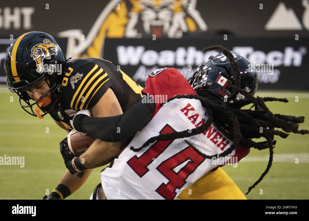 Ottawa RedBlacks défensif retour Abdul Kanneh (14) attaque le receveur de la série des Tiger Cats de Hamilton Jaelon Acklin (80) lors de la deuxième moitié du match de football de la CFL à Hamilton le samedi 23 octobre 2021. LA PRESSE CANADIENNE/Peter Power Banque D'Images