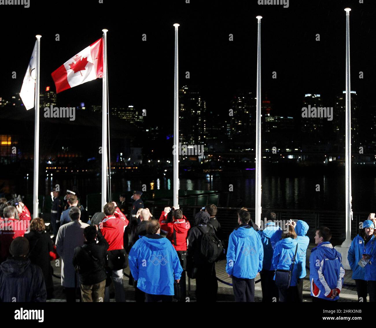 Les gens observent que le drapeau canadien est levé lors d'une cérémonie au village des athlètes olympiques, le mercredi 10 février 2010 à Vancouver. LA PRESSE CANADIENNE/Nathan Denette Banque D'Images