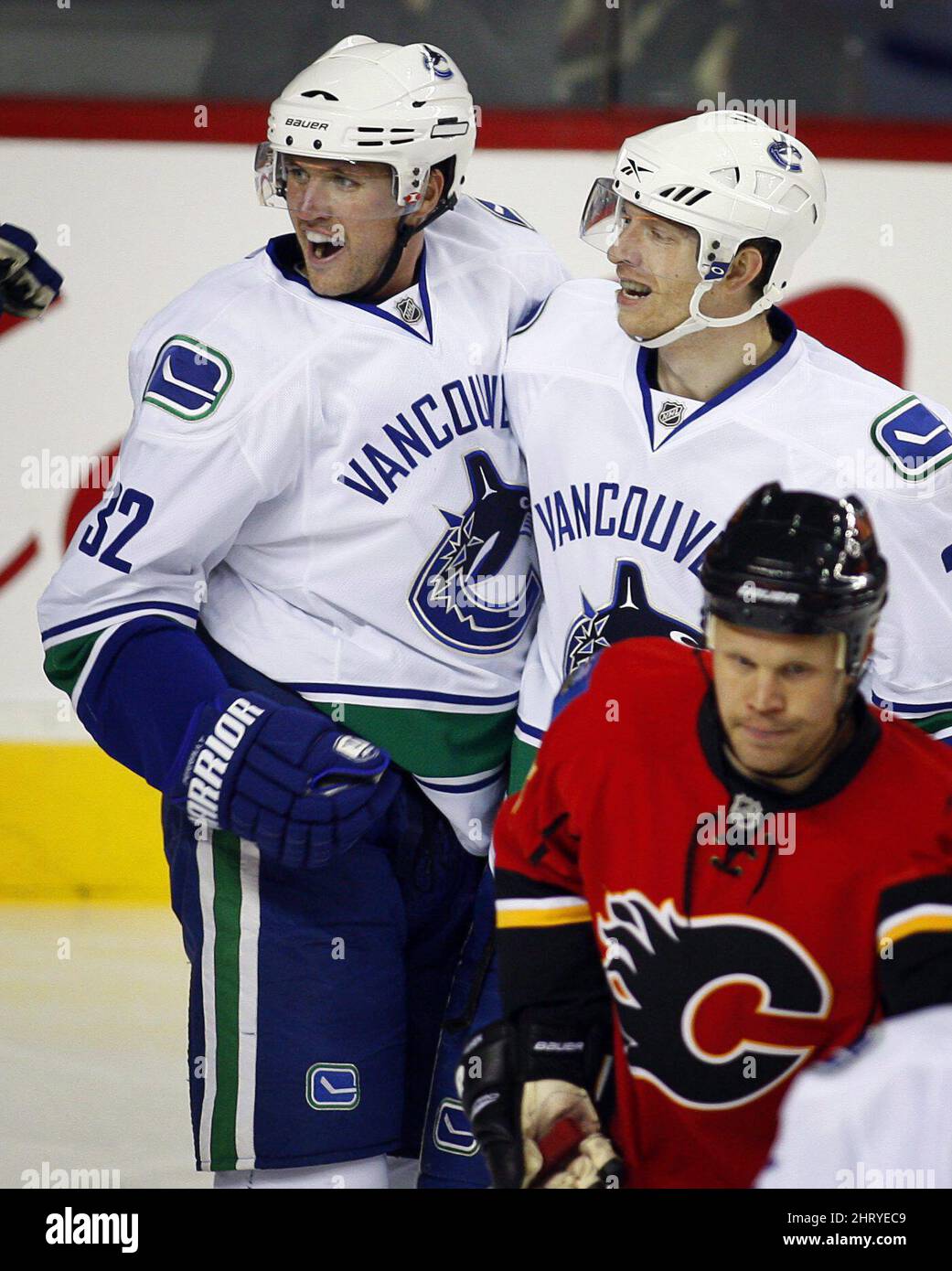 Jannik Hansen, au centre des Canucks de Vancouver, célèbre son but avec Joel Perrault, à gauche, alors que Oli Jokinen, de Calgary Flames, débarque pendant la première période de la LNH avant la saison, équipe de hockey fractionnée, à Calgary, le mardi 21 septembre 2010.LA PRESSE CANADIENNE/Jeff McIntosh Banque D'Images