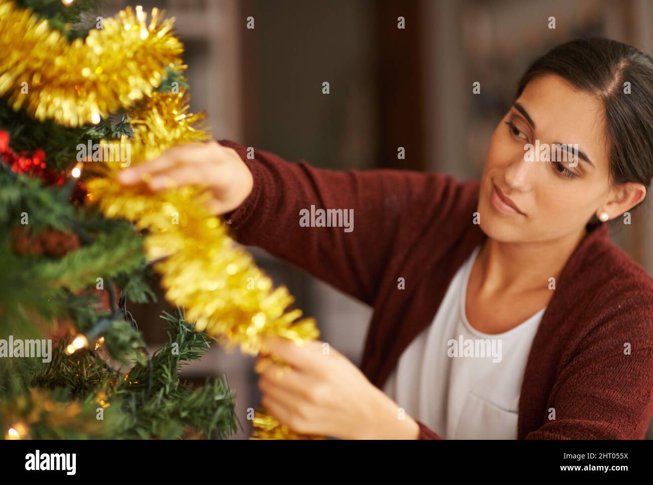 Ma partie préférée de la saison. Plan court d'une jeune femme attrayante décorant son arbre de Noël. Banque D'Images