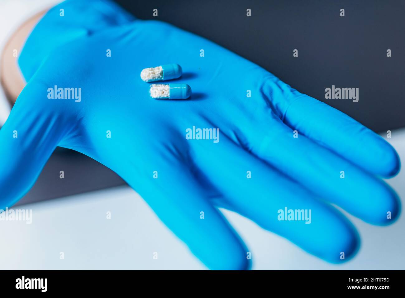 Main gantée tenant une vraie pilule et un placebo Banque D'Images