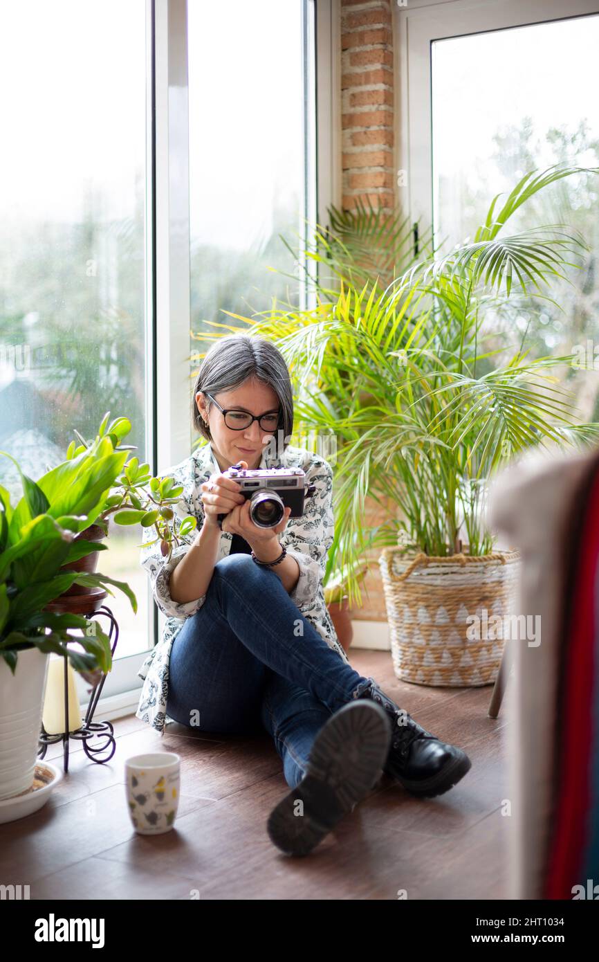 Femme adulte à la maison utilisant un appareil photo analogique. Espace pour le texte. Banque D'Images