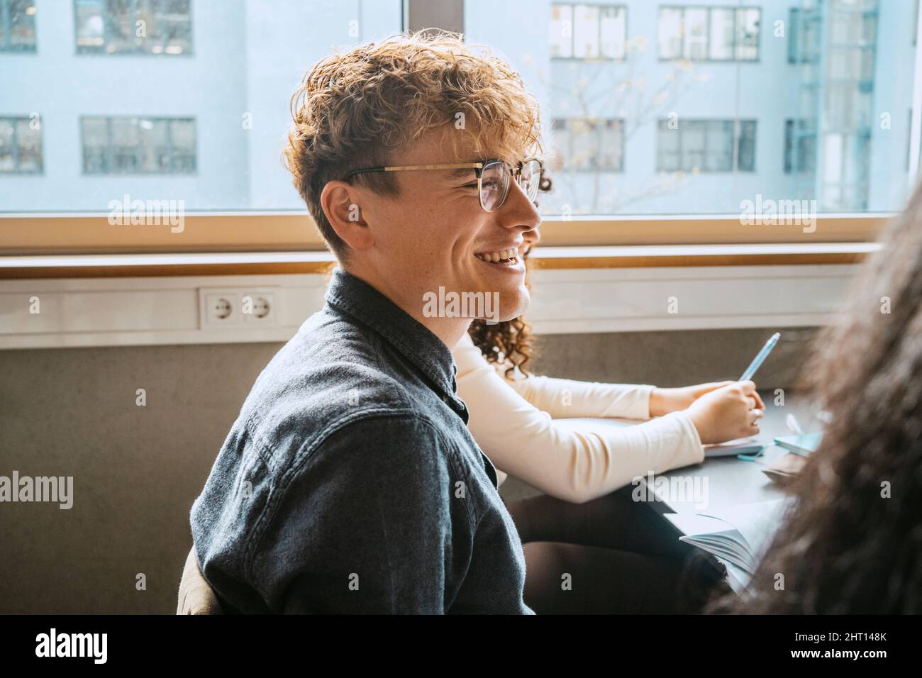 Vue latérale d'un jeune homme blond souriant portant des lunettes assis en  classe Photo Stock - Alamy
