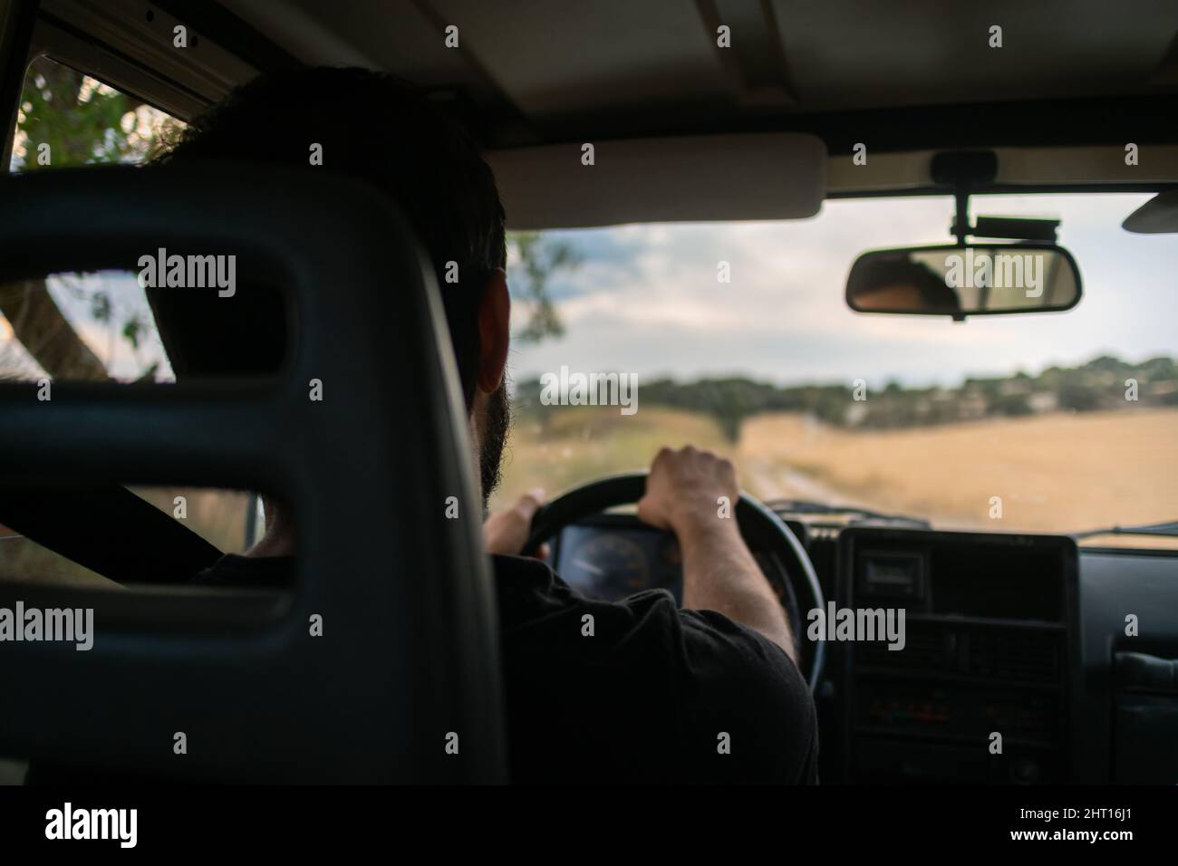 Jeune homme conduisant une voiture à quatre roues motrices dans la campagne, conducteur à l'intérieur de la cabine d'une voiture 4x4 , conduite sur une route non scellée, paysage rural dans SP Banque D'Images
