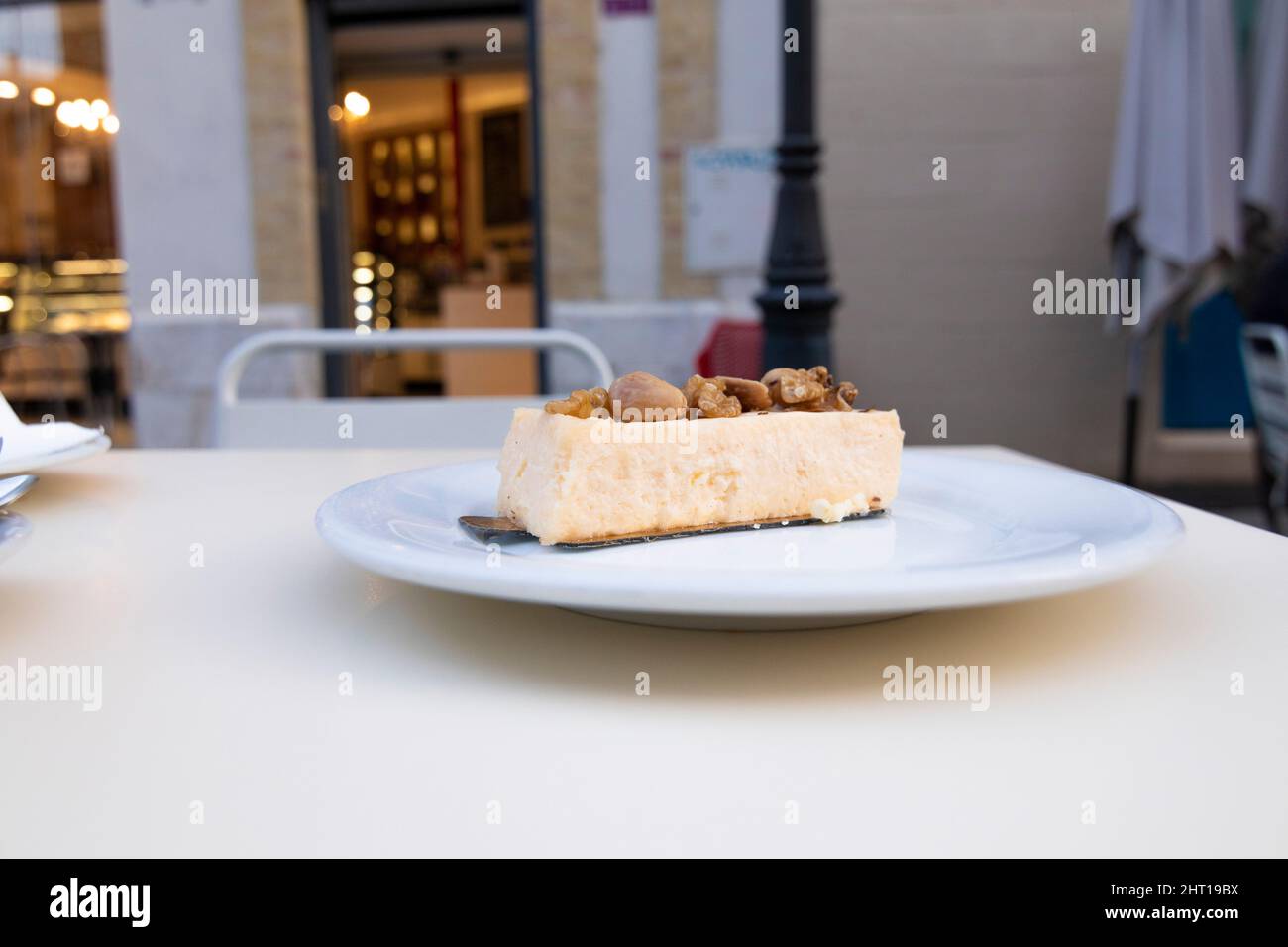 Morceau de cheesecake aux amandes sur une assiette, sur une table dans une cafétéria. Concept de confiserie. Banque D'Images