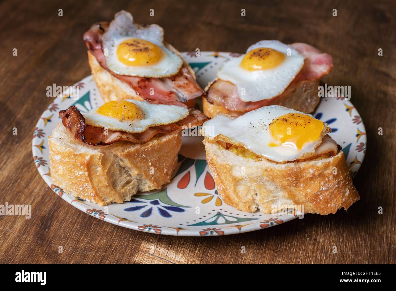 Tranche de pain avec bacon et œuf de caille grillé, sur une table en bois. Banque D'Images Tranche de pain avec bacon et œuf de caille grillé, sur une table en bois. Banque D'Images