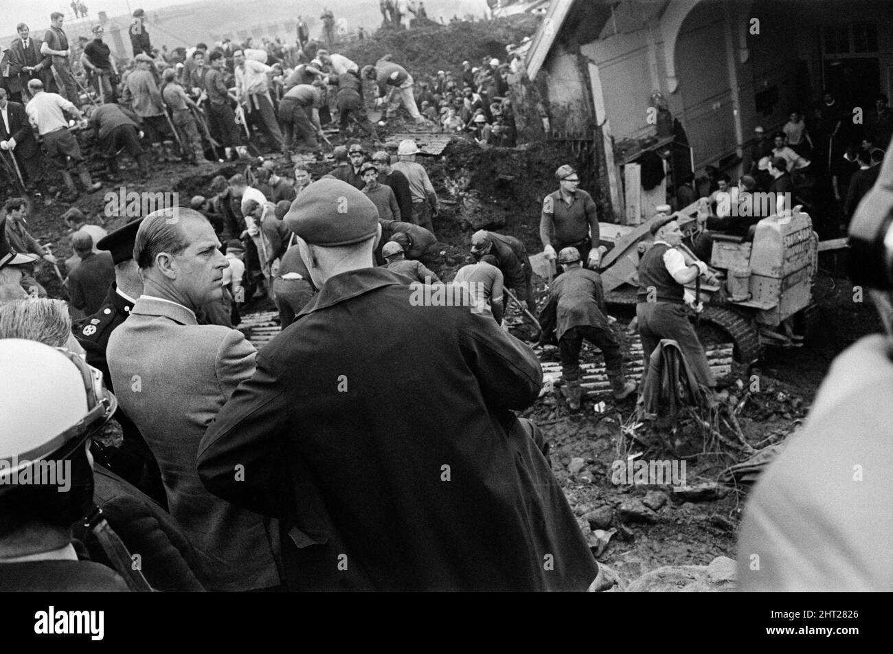 Aberfan, sud du pays de Galles, 22nd octobre 1966The le duc d'Édimbourg visite Aberfan, et est vu ici sur le site de la Pantans Junior School, en parlant avec les locaux à mesure que se poursuit l'effort de réutilisation et de récupération. 22nd octobre, le lendemain de la catastrophe du 21st octobre. Le désastre d'Aberfan a été l'effondrement catastrophique d'un pourboire de collierie dans le village gallois d'Aberfan, près de Merthyr Tydfil. Elle a été causée par une accumulation d'eau dans la roche accumulée et le schiste, qui a soudainement commencé à glisser en descente sous forme de lisier et a englouti la Pantglas Junior School ci-dessous, le 21st octobre 1966, tuant 116 ch Banque D'Images