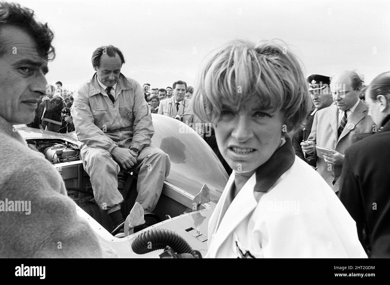 Proteus Bluebird, la voiture dans laquelle Donald Campbell a battu le record mondial de vitesse automobile a maintenant fait sa dernière course, à 5 km/h, à la station RAF, Debden, Essex, 19th juin 1966. Campbell devait faire une démonstration lors d'un gala, Mais 5 jours plus tôt, la voiture a été gravement endommagée quand, avec le pilote de course Peter Bolton aux commandes, elle a heurté une clôture en bois et une haie à 100 km/h, a navigué 10ft dans les airs en traversant la route de Cambridge Chelsford et a finalement tourné sur un terrain de 200 mètres. Également en photo, la femme Tonia Campbell. Banque D'Images