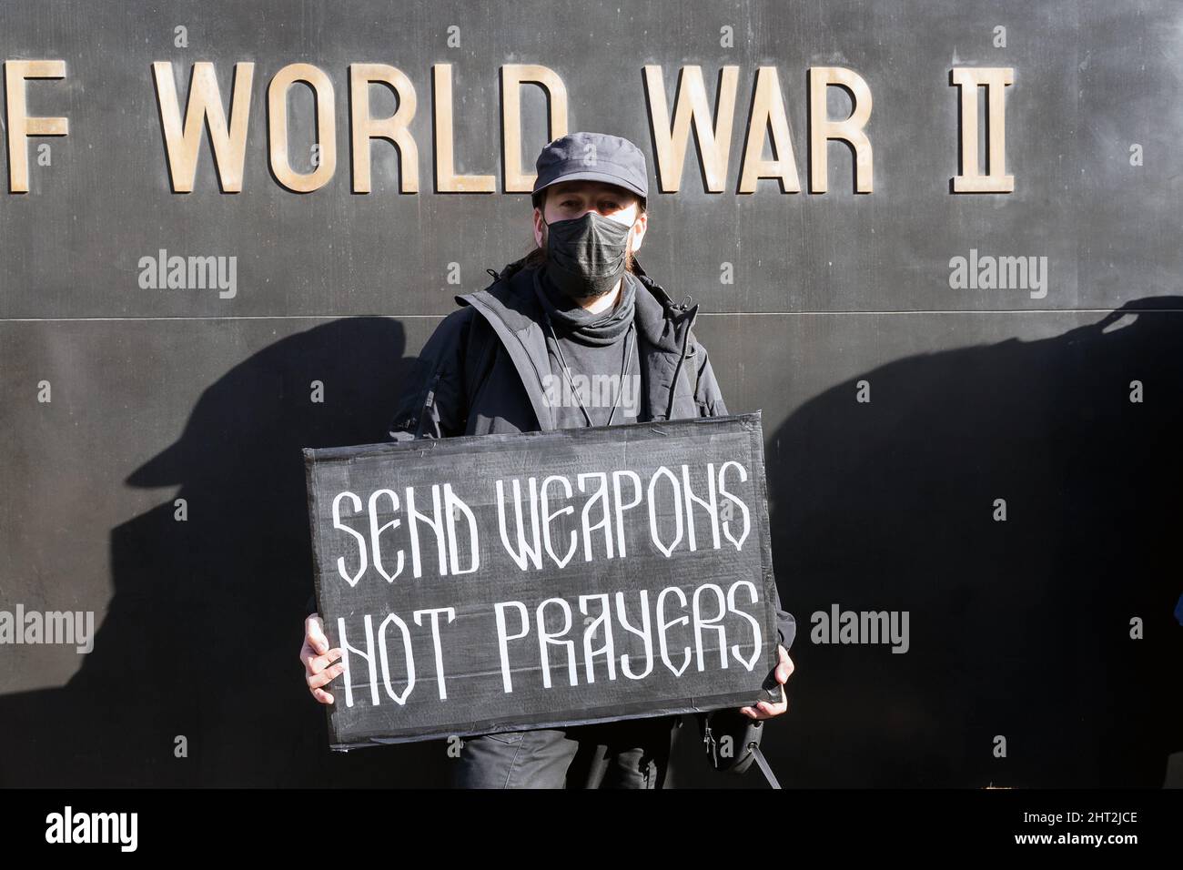 Protestation contre l'invasion russe de l'Ukraine à Londres. Un manifestant masculin debout devant la femme du mémorial de la guerre mondiale de 2 tenant une bannière Banque D'Images