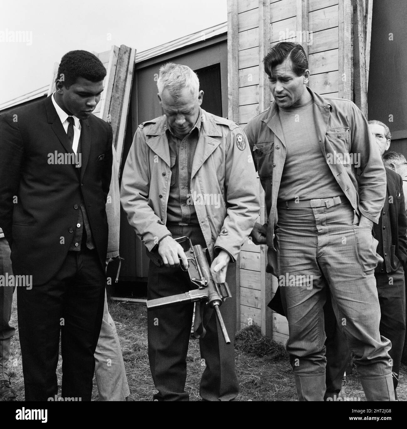 Muhammad Ali (Cassius Clay), a pris une pause avant son combat de titre prochain avec Brian Londres. Clay a rendu visite à l'ensemble du film de Beechwood Park School, Markyate, Hertfordshire. Où MGN filmait des séquences de « la sale douzaine ». (Photo) Muhammad Ali et Clint Walker G.I. regardant le major Lee Marvin (au centre) avec un fusil. 6th août 1966 Banque D'Images