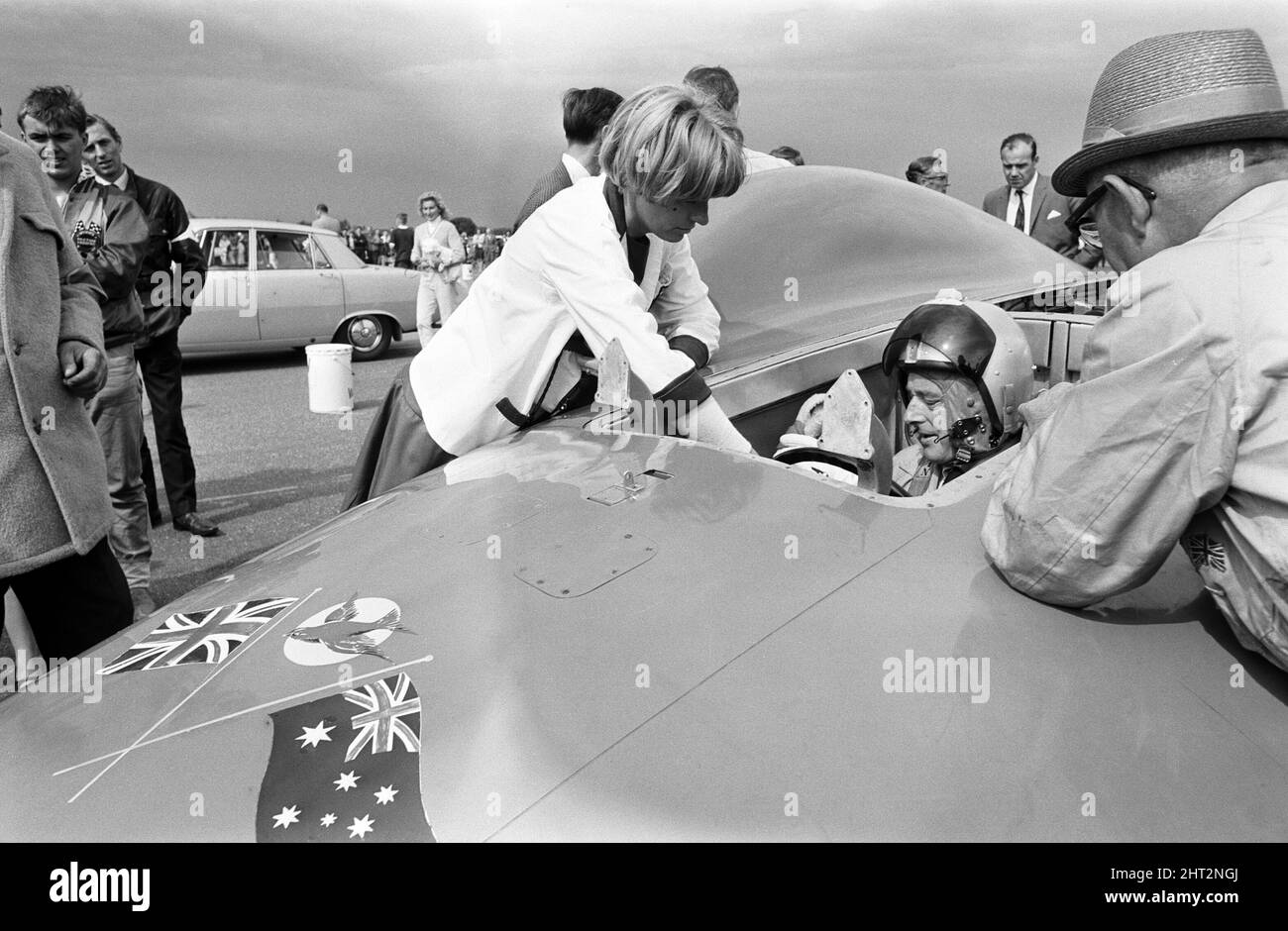 Proteus Bluebird, la voiture dans laquelle Donald Campbell a battu le record mondial de vitesse automobile a maintenant fait sa dernière course, à 5 km/h, à la station RAF, Debden, Essex, 19th juin 1966. Campbell devait faire une démonstration lors d'un gala, Mais 5 jours plus tôt, la voiture a été gravement endommagée quand, avec le pilote de course Peter Bolton aux commandes, elle a heurté une clôture en bois et une haie à 100 km/h, a navigué 10ft dans les airs en traversant la route de Cambridge Chelsford et a finalement tourné sur un terrain de 200 mètres. Également en photo, la femme Tonia Campbell. Banque D'Images
