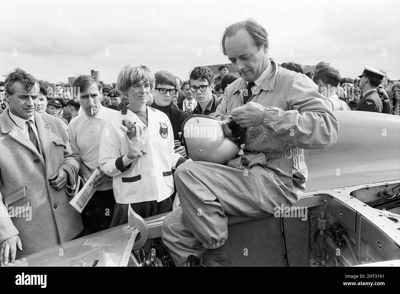 Proteus Bluebird, la voiture dans laquelle Donald Campbell a battu le record mondial de vitesse automobile a maintenant fait sa dernière course, à 5 km/h, à la station RAF, Debden, Essex, 19th juin 1966. Campbell devait faire une démonstration lors d'un gala, Mais 5 jours plus tôt, la voiture a été gravement endommagée quand, avec le pilote de course Peter Bolton aux commandes, elle a heurté une clôture en bois et une haie à 100 km/h, a navigué 10ft dans les airs en traversant la route de Cambridge Chelsford et a finalement tourné sur un terrain de 200 mètres. Également en photo, la femme Tonia Campbell. Banque D'Images
