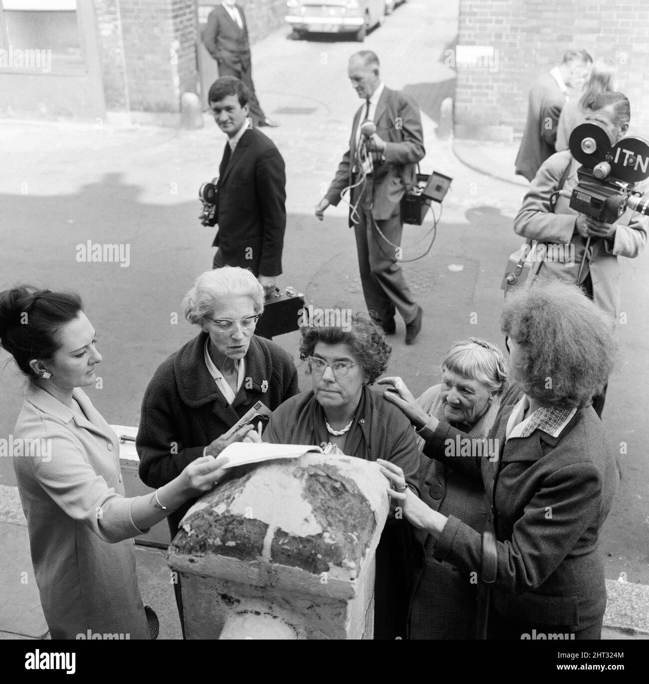 John Edward Witney, 36 ans, qui a été accusé du meurtre de 3 policiers, a été emmené du poste de police de Shepherds Bush (le QG du meurtre) et conduit au tribunal de la magistrature de West London, où il a fait une brève comparution et a été remis en détention jusqu'en août 23. Quelques minutes après avoir été conduit par des femmes de cour, il faut à tour de rôle signer une pétition pour ramener la peine de mort pour meurtre. 16th août 1966. Banque D'Images