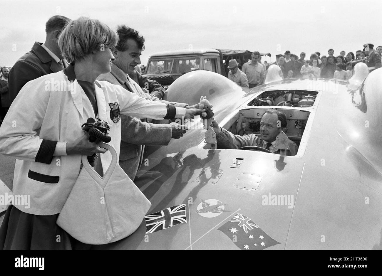 Proteus Bluebird, la voiture dans laquelle Donald Campbell a battu le record mondial de vitesse automobile a maintenant fait sa dernière course, à 5 km/h, à la station RAF, Debden, Essex, 19th juin 1966. Campbell devait faire une démonstration lors d'un gala, Mais 5 jours plus tôt, la voiture a été gravement endommagée quand, avec le pilote de course Peter Bolton aux commandes, elle a heurté une clôture en bois et une haie à 100 km/h, a navigué 10ft dans les airs en traversant la route de Cambridge Chelsford et a finalement tourné sur un terrain de 200 mètres. Également en photo, la femme Tonia Campbell. Banque D'Images