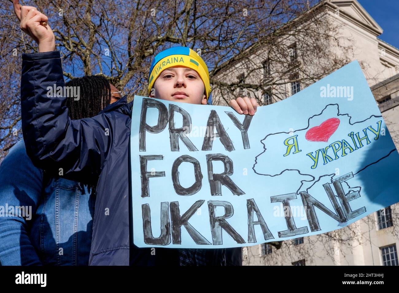 26th février 2022 : des ressortissants ukrainiens et des partisans pro-ukrainiens se rassemblent à Whitehall pour protester contre l'invasion russe de l'Ukraine. Londres, Royaume-Uni. En photo : un jeune garçon se tient au-dessus de la foule en tenant un écriteau pour les prières pour l'Ukraine. Banque D'Images