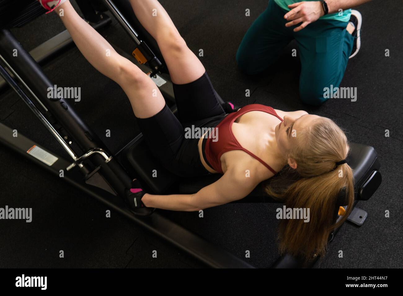 L'entraînement dirigé par un instructeur aide un beau client à effectuer des exercices dans un club de remise en forme, le concept de jouer du sport avec un loisir professionnel de gym Banque D'Images