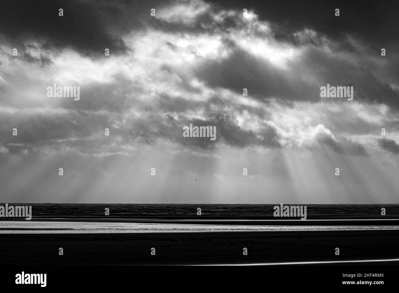 Prise de vue en niveaux de gris du Camber Sands entouré par la mer à Rye, Angleterre, Royaume-Uni Banque D'Images