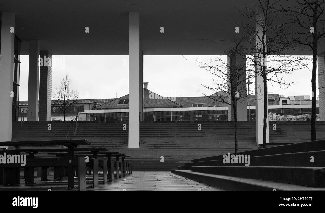 Photo en niveaux de gris de sièges vides devant un bâtiment moderne Banque D'Images