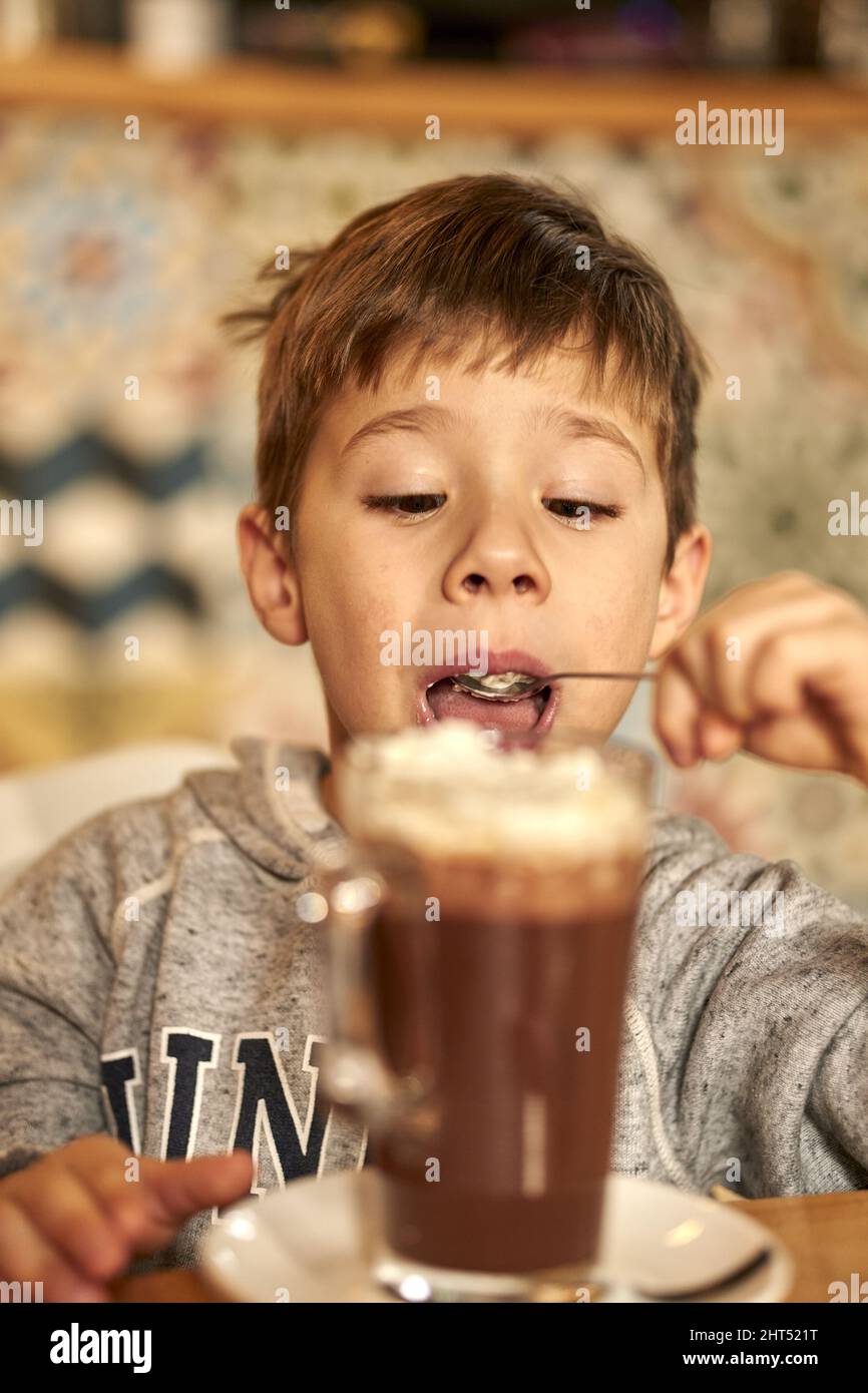 Photo verticale d'un enfant du Caucase qui boit du lait au chocolat dans un café Banque D'Images