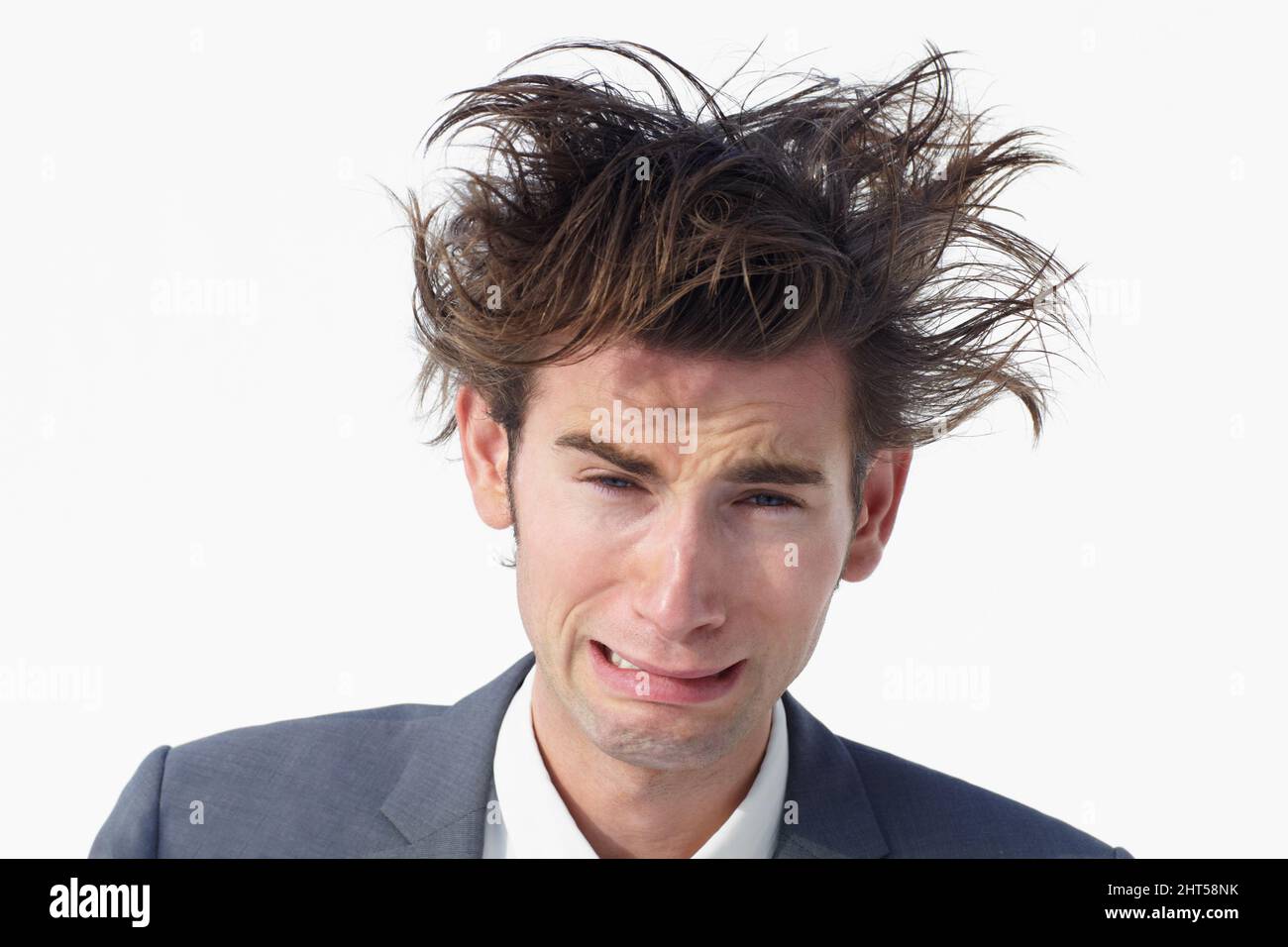 J'ai besoin d'aide. Un jeune homme d'affaires avec des cheveux désordonnés qui se hissent tout en étant isolé sur blanc. Banque D'Images