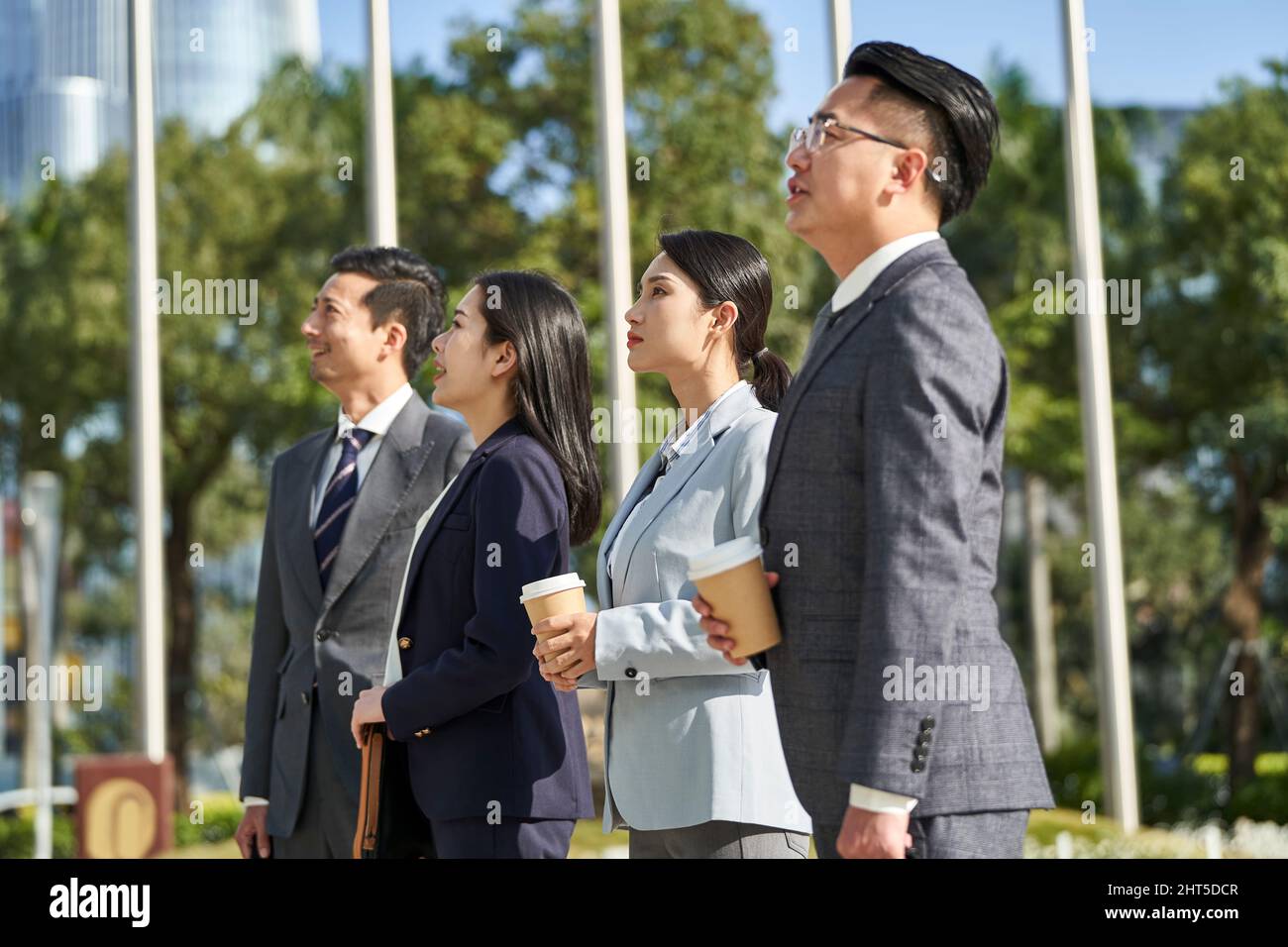 groupe de quatre jeunes gens d'affaires asiatiques marchant à l'extérieur dans la rue dans la ville moderne Banque D'Images