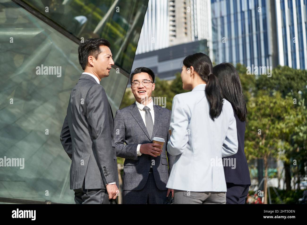 groupe de quatre jeunes hommes d'affaires asiatiques qui discutent à l'extérieur dans la rue Banque D'Images
