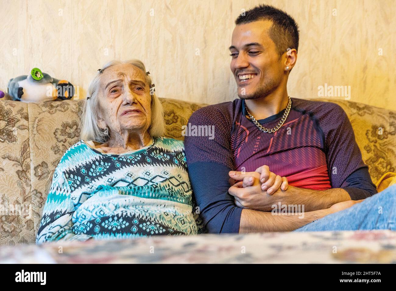 Berlin, Allemagne. 17th févr. 2022. Agnes Jeschke (l), est assise avec sa colocataire Amir Farahani (r) sur le canapé derrière la table basse dans le salon de son appartement. Malgré son âge avancé, elle ne veut pas quitter son appartement bien-aimé de Berlin. Il est à la recherche urgente d'un endroit où séjourner. Une annonce Internet rassemble les deux - malgré une différence d'âge de plus de 70 ans. (À dpa 'plus de 70 ans de différence et pourtant assez beaucoup de meilleurs amis") Credit: Carsten Koall/dpa/Alamy Live News Banque D'Images