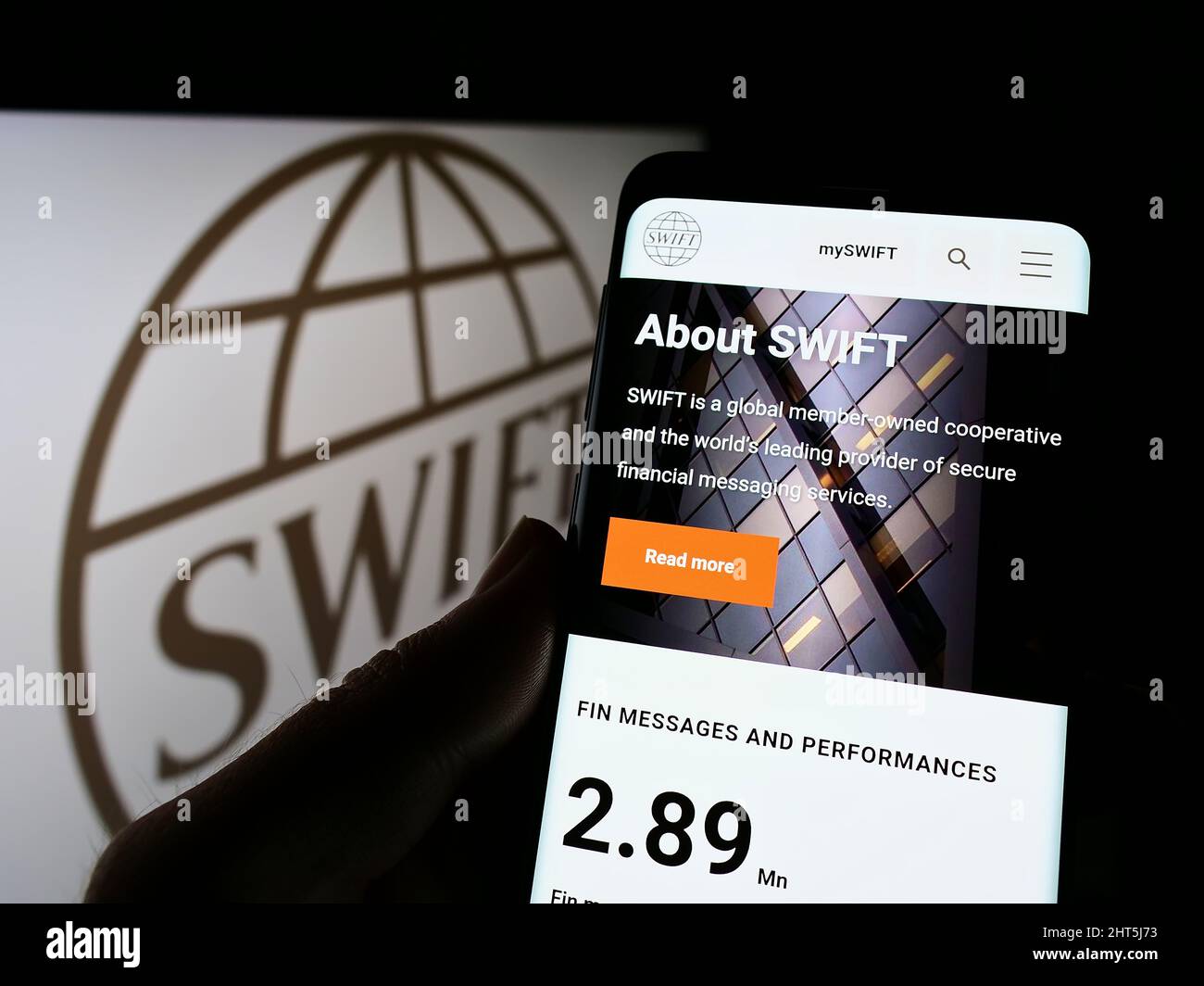 Personne tenant un téléphone portable avec le site Web du système de transaction bancaire SWIFT à l'écran devant le logo. Concentrez-vous sur le centre de l'écran du téléphone. Banque D'Images