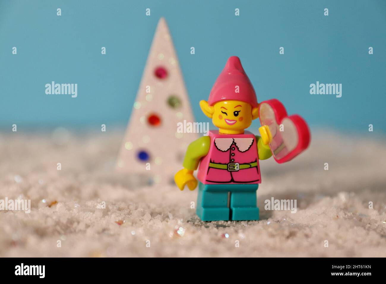 Jolie figurine Lego sur paillettes blanches à côté d'un sapin de Noël en carton découpé. Banque D'Images