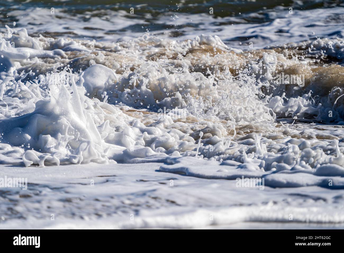 Vagues se brisant avec de la mousse de mer sur la plage Banque D'Images