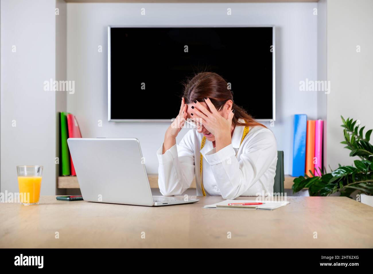 Jeune femme nutritionniste travaillant sur le côté avec une expression douteuse et sceptique. Le médecin du Dietologue s'est défait et s'est frustré de la main sur la tête Banque D'Images