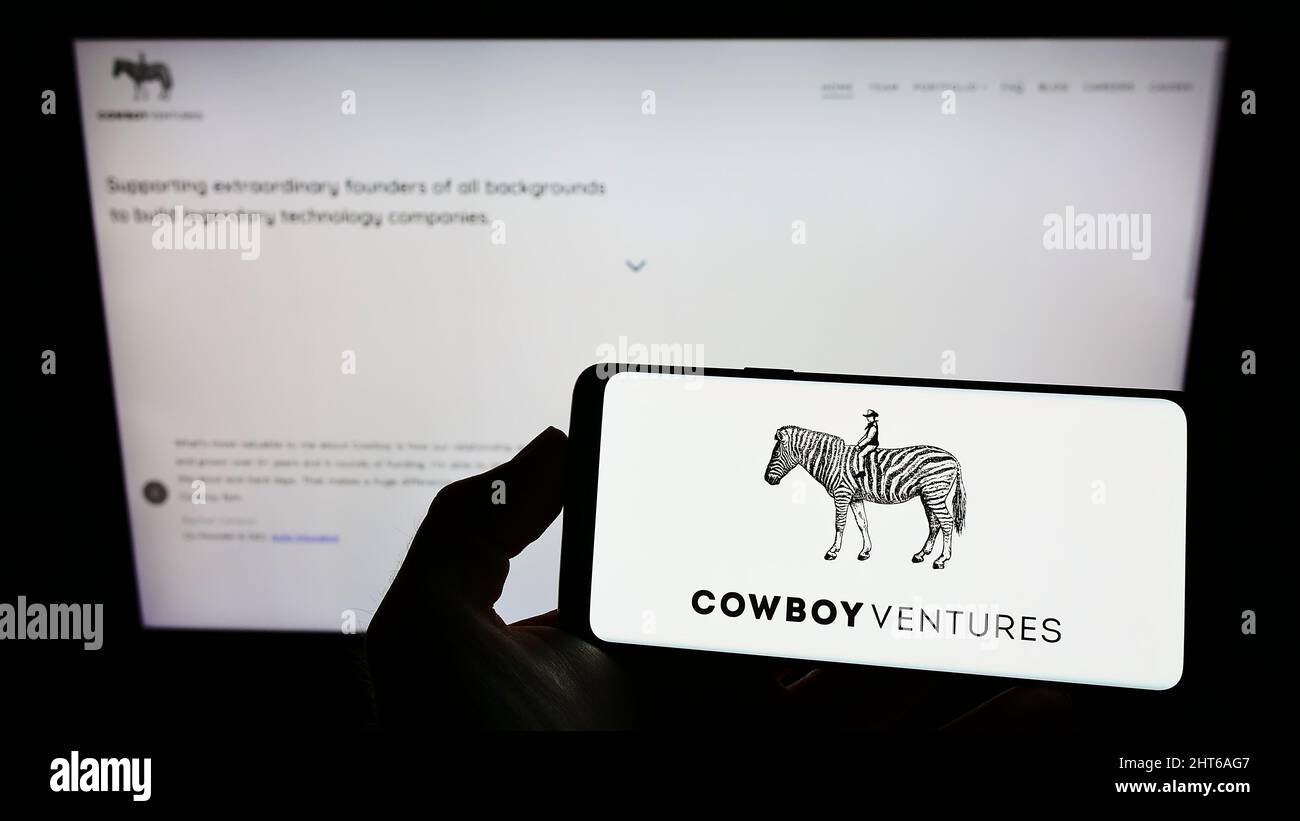 Personne tenant un smartphone avec le logo de la société de capital-risque américaine Cowboy Ventures à l'écran devant le site Web. Mise au point sur l'affichage du téléphone. Banque D'Images Personne tenant un smartphone avec le logo de la société de capital-risque américaine Cowboy Ventures à l'écran devant le site Web. Mise au point sur l'affichage du téléphone. Banque D'Images
