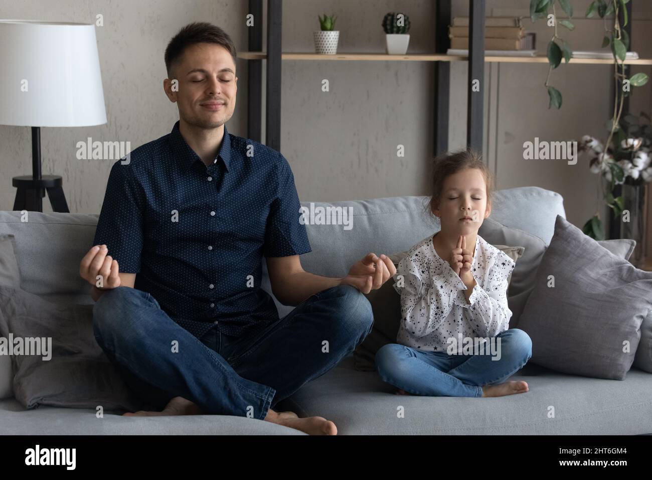 Un jeune père heureux fait des exercices de yoga avec une petite fille. Banque D'Images