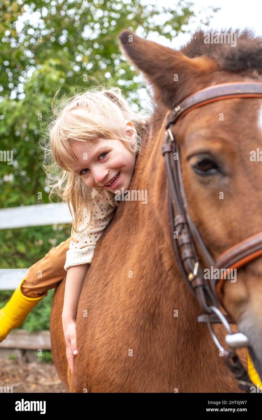 petite fille câlins cheval poney et rire heureux Banque D'Images
