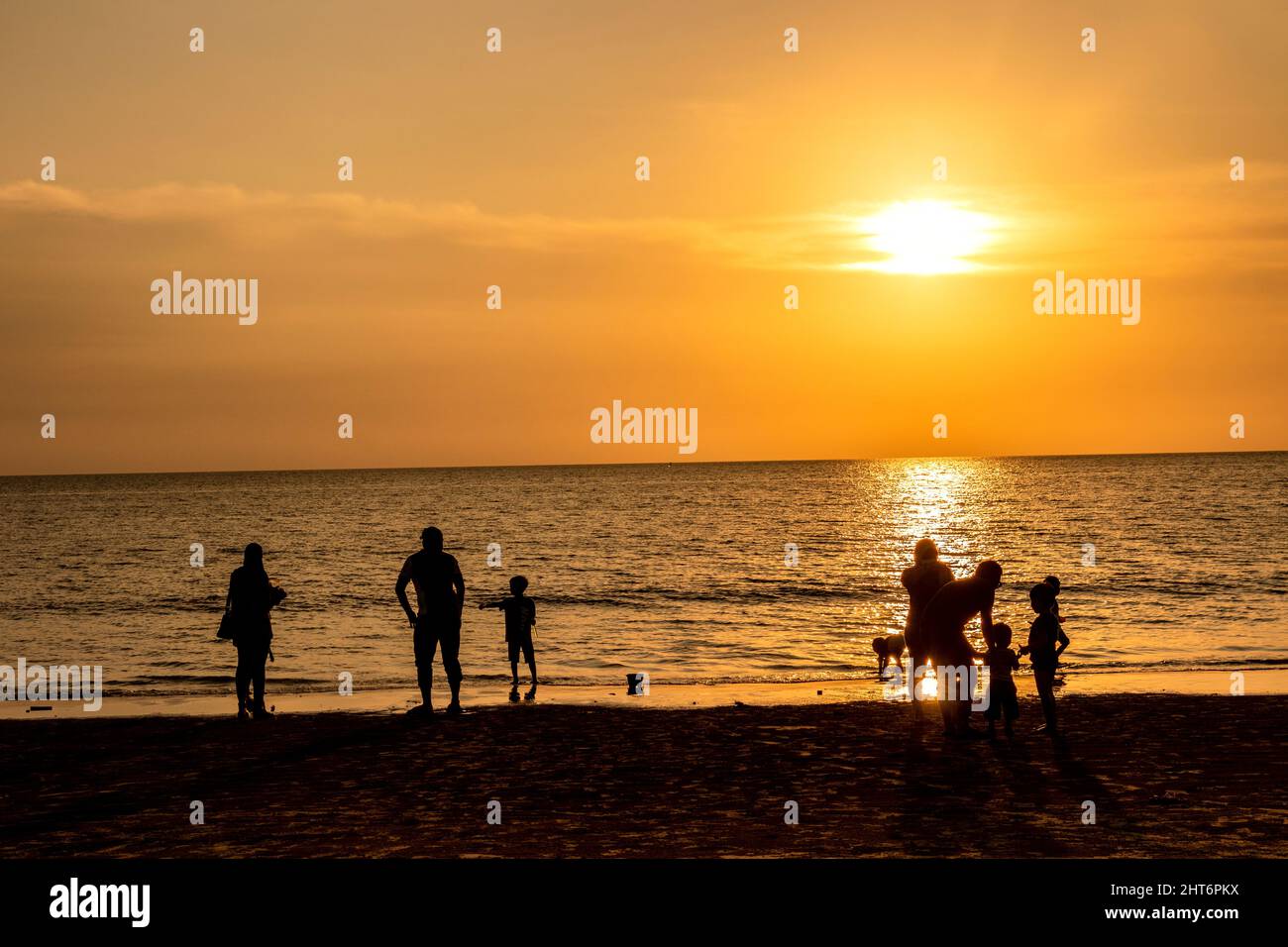 Familles et couples profitant du coucher du soleil sur la plage de Tajung Aru Sabah Bornéo Malaisie Banque D'Images