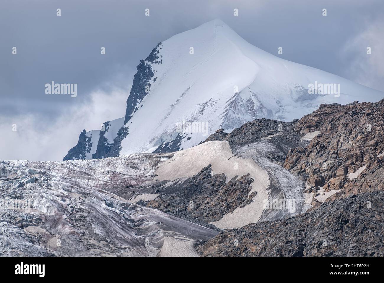 Vue pittoresque avec un sommet de montagne, un relief d'un glacier avec des fissures, des failles, de la glace et de la neige et de petites figures de grimpeurs allant au sommet. Altaï, Banque D'Images