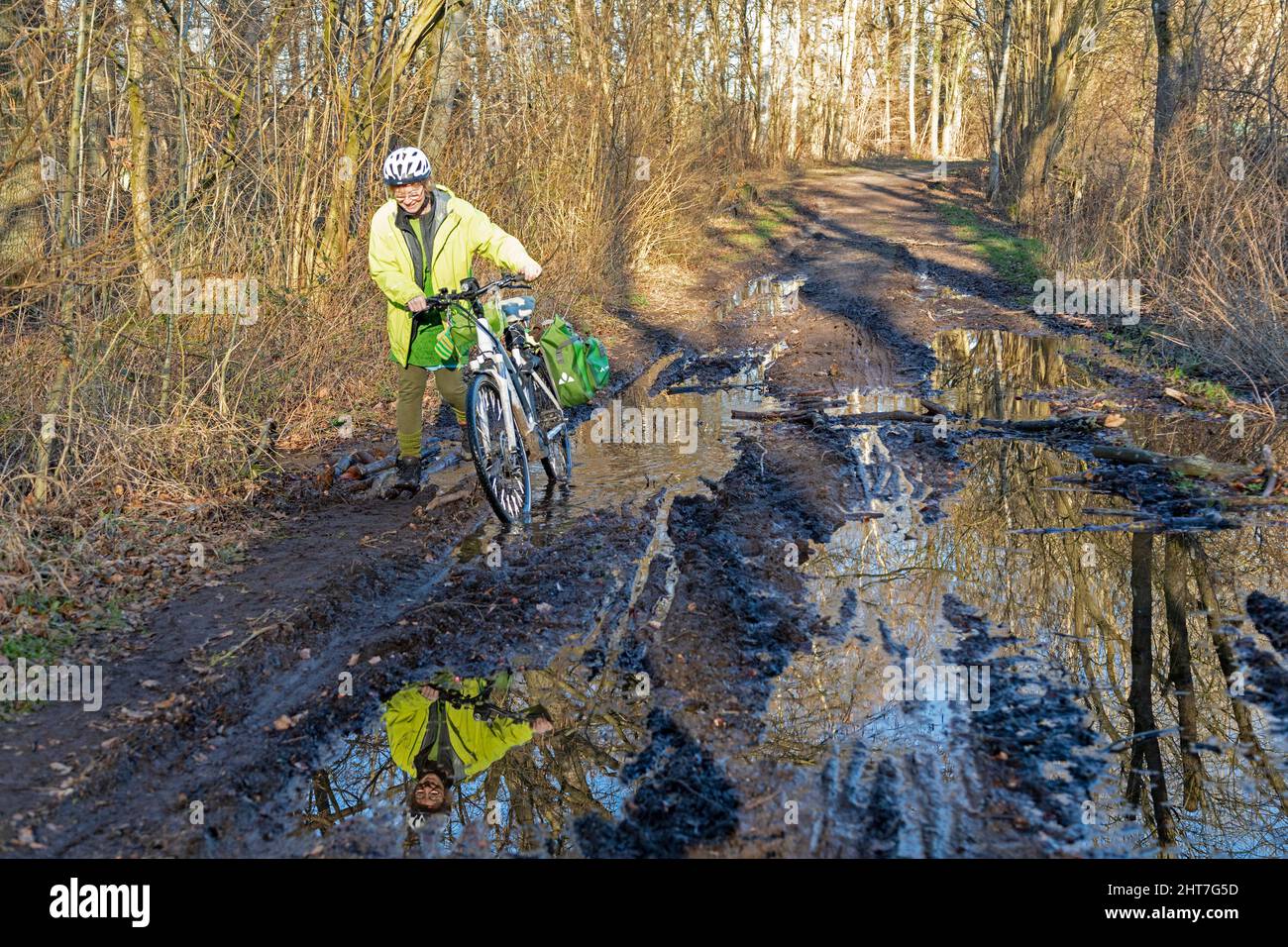 Femme de plus de cinquante ans faisant une tournée à vélo avec son e-vélo le long d'un sentier boueux et à travers des flaques, Lueneburg, Basse-Saxe, Allemagne Banque D'Images