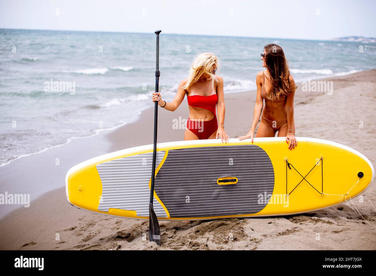 Deux jolies jeunes femmes avec paddle-board sur la plage un jour d'été Banque D'Images