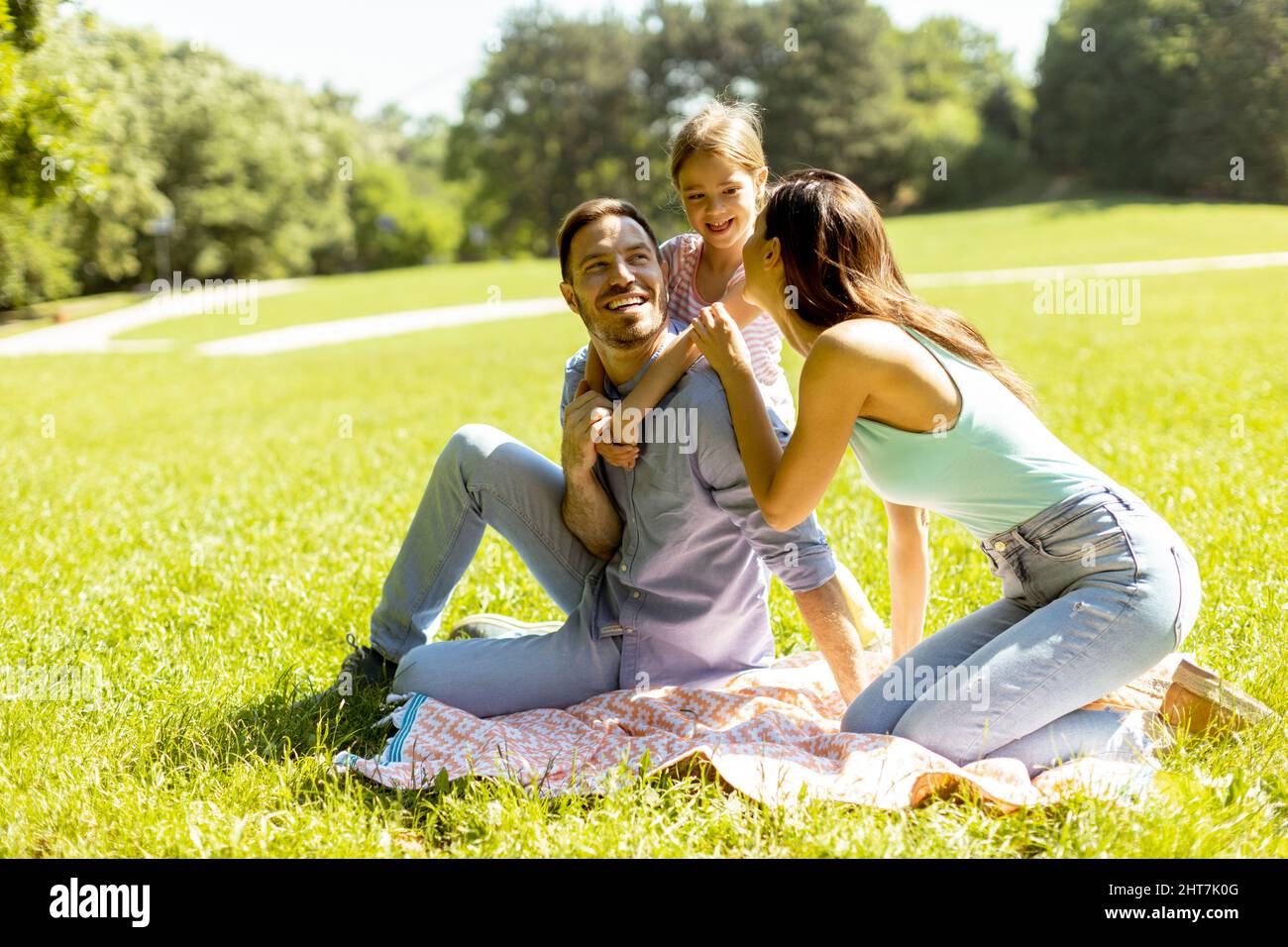 Bonne jeune famille avec petite fille mignonne s'amuser dans le parc par une journée ensoleillée Banque D'Images