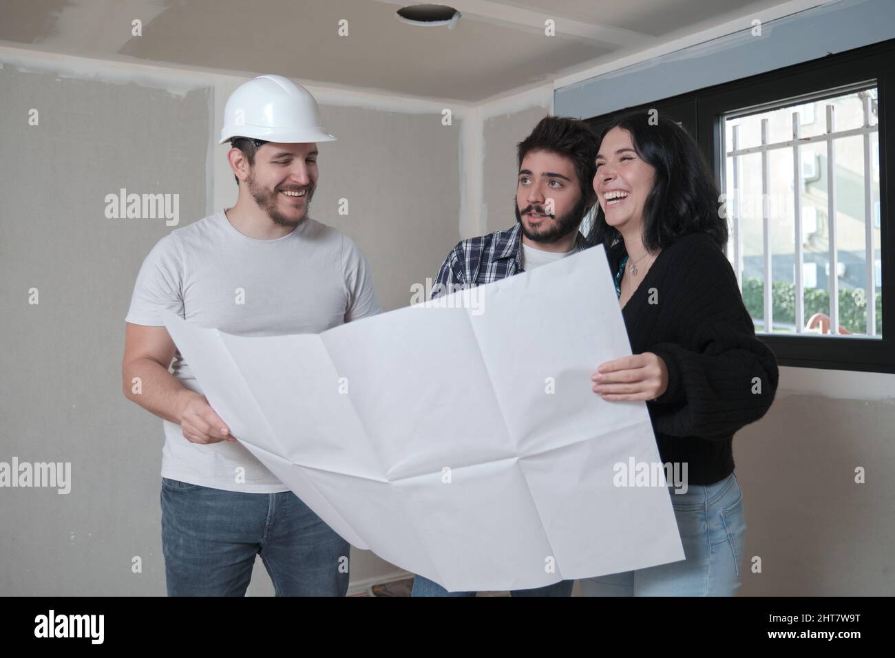 L'architecte montre l'appartement dans des plans de construction à un couple heureux intéressé. Banque D'Images
