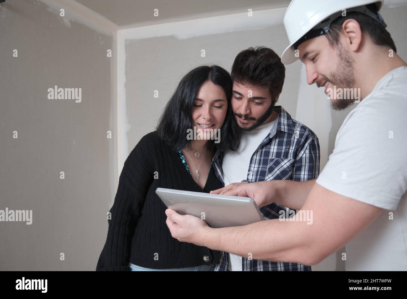 L'architecte montre l'appartement dans les plans de construction dans une tablette à ses clients. Banque D'Images