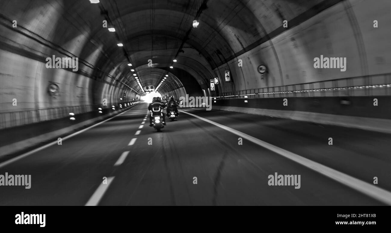 Les motocyclistes passent la route par un tunnel Banque D'Images